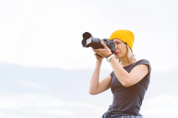 Retrato de um fotógrafo profissional ao ar livre. Uma fotógrafa tira fotos de sua câmera em sua câmera. Trevors Foto — Fotografia de Stock