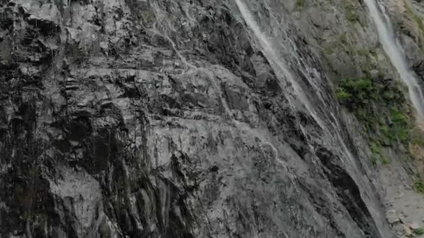 Seguimiento y plano superior Air disparó desde una corriente de agua salpicando cascada en una pared de roca en las montañas del Cáucaso. Alrededor del chorro de la cascada — Vídeos de Stock