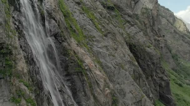 Seguimiento y plano superior Air disparó desde una corriente de agua salpicando cascada en una pared de roca en las montañas del Cáucaso. Alrededor del chorro de la cascada — Vídeos de Stock