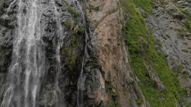 Bijhouden en top shot lucht geschoten uit een stroom van water nat van de waterval op een rotswand in de bergen van de Kaukasus. Rond de straal van de waterval — Stockvideo