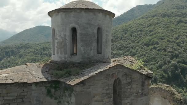 高い山に立っている古代の老朽化したキリスト教会からドローン上出発。空撮。北のコーカサス。ロシア — ストック動画