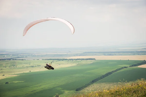 Parapente naranja blanco con un parapente en un capullo sobre el fondo de los campos del cielo y las nubes. Deportes de Parapente — Foto de Stock