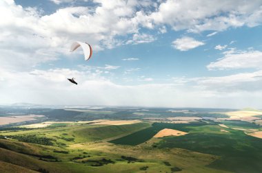Bir koza arka planı, gökyüzü ve bulutlar bir yamaçparaşütü ile beyaz turuncu paraglide. Yamaç paraşütü spor