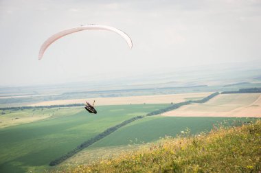Bir koza arka planı, gökyüzü ve bulutlar bir yamaçparaşütü ile beyaz turuncu paraglide. Yamaç paraşütü spor