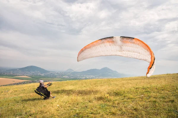 The paraglider opens his parachute before taking off from the mountain in the North Caucasus. Filling the parachute wing with air before takeoff — Stock Photo, Image