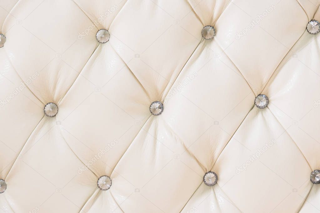 Beige soft tapestry pattern background with symmetrical buttons on the corners of diamonds. Soft and expensive furniture elements. Luxury background