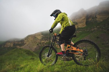 Bir adam bir dağ bisikleti binme bir dağ kask içinde güzel doğa bulutlu havalarda sürmek. yokuş aşağı