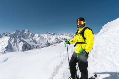 Arka planı karla kaplı Dağları'nın karlı bir yamaç üzerinde duran bir profesyonel freerider kayakçı portresi. Kış sporları kavramı