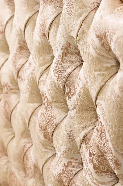 Beige soft tapestry pattern background with symmetrical buttons on the corners of diamonds. Soft and expensive furniture elements. Luxury background