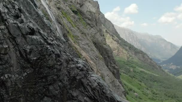 Seguimiento y plano superior Air disparó desde una corriente de agua salpicando cascada en una pared de roca en las montañas del Cáucaso. Alrededor del chorro de la cascada — Vídeo de stock