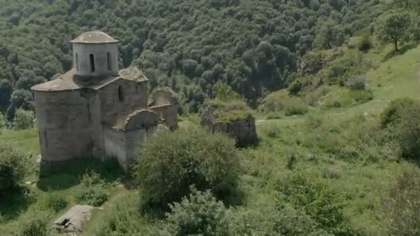 Partenza su un drone sopra l'antica chiesa cristiana fatiscente in piedi in alto sulla montagna. Vista aerea. Caucaso settentrionale. Russia — Video Stock