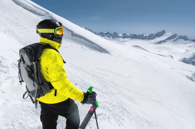 Arka planı karla kaplı Dağları'nın karlı bir yamaç üzerinde duran bir profesyonel freerider kayakçı portresi. Kış sporları kavramı