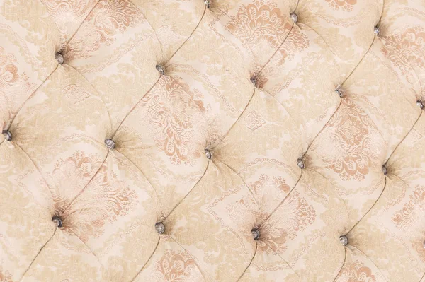 Beige soft tapestry pattern background with symmetrical buttons on the corners of diamonds. Soft and expensive furniture elements. Luxury background