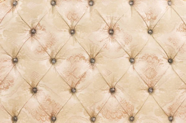 Beige soft tapestry pattern background with symmetrical buttons on the corners of diamonds. Soft and expensive furniture elements. Luxury background