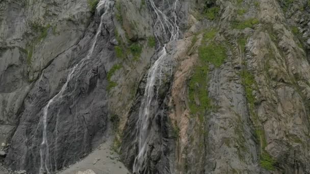 Seguimiento y plano superior Air disparó desde una corriente de agua salpicando cascada en una pared de roca en las montañas del Cáucaso. Alrededor del chorro de la cascada — Vídeos de Stock