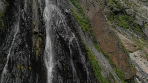 Seguimiento y plano superior Air disparó desde una corriente de agua salpicando cascada en una pared de roca en las montañas del Cáucaso. Alrededor del chorro de la cascada — Vídeos de Stock