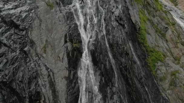 Seguimiento y plano superior Air disparó desde una corriente de agua salpicando cascada en una pared de roca en las montañas del Cáucaso. Alrededor del chorro de la cascada — Vídeos de Stock