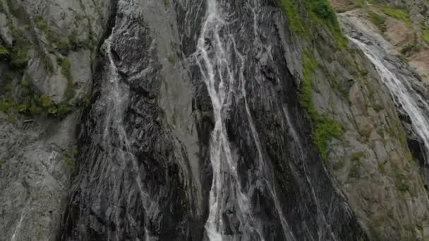 Bijhouden en top shot lucht geschoten uit een stroom van water nat van de waterval op een rotswand in de bergen van de Kaukasus. Rond de straal van de waterval — Stockvideo