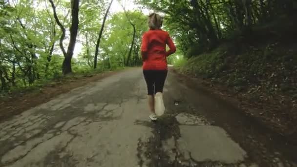 Бегущая девушка. Блондинка занимается спортом на свежем воздухе в летнем лесу. Широкий угол замедленной съемки — стоковое видео