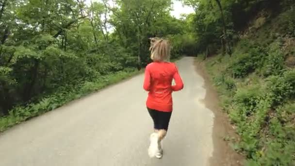 Chica corriendo. Chica rubia haciendo deportes al aire libre en el bosque de verano. Vista trasera de cámara lenta gran angular — Vídeos de Stock