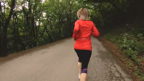 Chica corriendo. Chica rubia haciendo deportes al aire libre en el bosque de verano. Vista trasera de cámara lenta gran angular — Vídeos de Stock