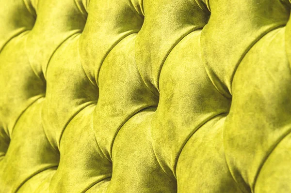 Kadife koltuk yakın çekim yüzey. Eğitim donanımları-kadife paspaslar düğmeleri ile sıkılır. Sarı chesterfield stil kapitone döşeme arka planı kapat