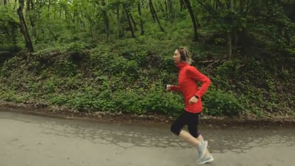 Running girl. Menina loira fazendo esportes ao ar livre na floresta de verão. Visão lateral ângulo largo de câmera lenta — Vídeo de Stock