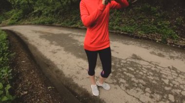 Genç çekici kadın kulaklık önünde akıllı izlemek veya yeşil orman yol koşu psole ayarlarını değiştirme