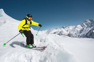 Profesyonel kayakçı kış mavi gökyüzü ve dağlar karşı buzul atlama önce hızda