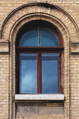 Sarı tuğla duvarına Vintage kemerli pencere. Siyah cam bir kestane rengi koyu kırmızı ahşap çerçeve içinde. Öğeleri bina antika vintage Mimarlık kavramı.