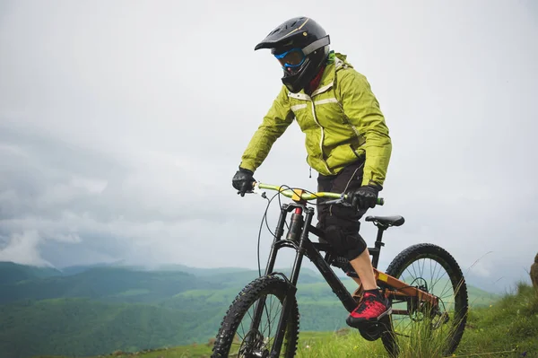 Un uomo in casco da montagna in sella a una mountain bike gira intorno alla splendida natura con il tempo nuvoloso. discesa in discesa — Foto Stock