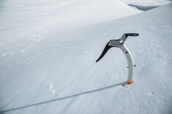 Close-up de um machado de gelo na neve com montanhas cobertas de neve no fundo — Fotografia de Stock