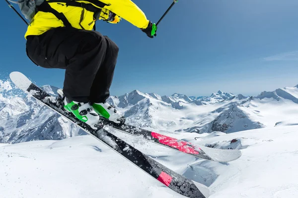En skidåkare i full sport utrustning hoppar ner i avgrunden av glaciären mot bakgrund av den blå himlen och de snöklädda bergen kaukasiska uppifrån. Visa från baksidan. Elbrus regionen — Stockfoto