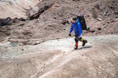 Bir sırt çantası ile bir dağcı çatlaklar dağ arasında elinde kaldırımlar ile tozlu bir buzul boyunca yürüyüş krampon içeri girer