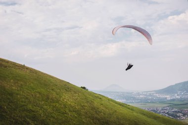 Beyaz-turuncu yamaçparaşütü dağlık arazi üzerinde uçar