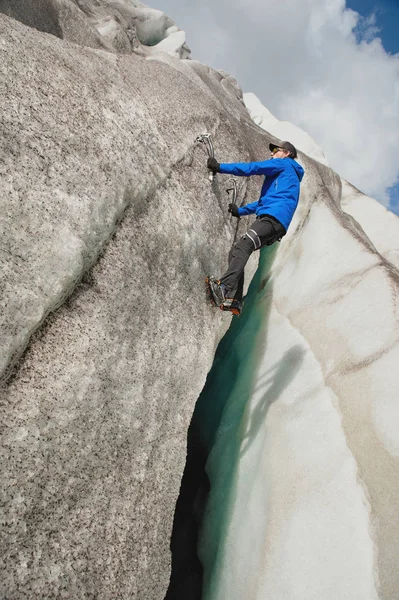 A free climber without insurance with two ice axes rises from a crack in the glacier. Free climbing without ropes — Stock Photo, Image