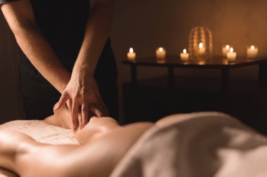 Yakın çekim erkek el buzağı masaj mum içinde belgili tanımlık geçmiş ile karanlık bir odada kadın bacak yapıyor. Kozmetik ve spa bakımları.