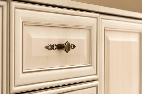 Close-up element of the drawer in the cabinet with a metal handle and wooden patterns. Detail of new furniture