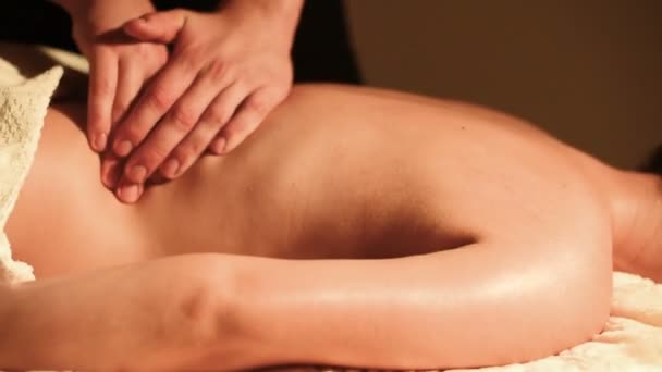 Close-up male hands doing healing massage with oil to a young girl in a dark cosmetology office. Dark key — Stock Video