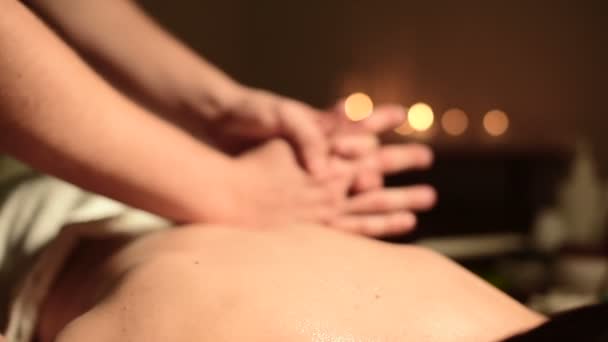 Mâini de sex masculin apropiate care fac masaj de vindecare cu ulei pentru o fată tânără într-un birou de cosmetologie întunecată. Cheia întunecată — Videoclip de stoc