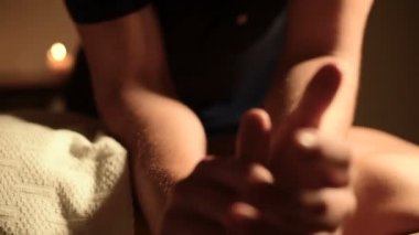 Yakın çekim Spa Masaj düşük açılı. Erkek masaj terapisti onun dirsek mumlar yanan arasında koyu bir Office ile genç bir kız için sırt ve omuz masaj yapıyor
