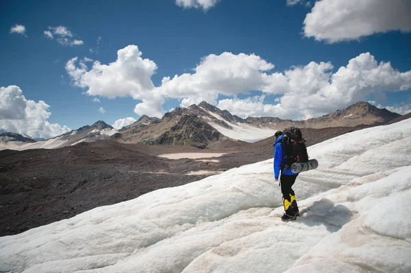 Góral z plecakiem spacery w raki spaceru wzdłuż zakurzonych lodowiec z chodników w rękach między pęknięcia w góry — Zdjęcie stockowe