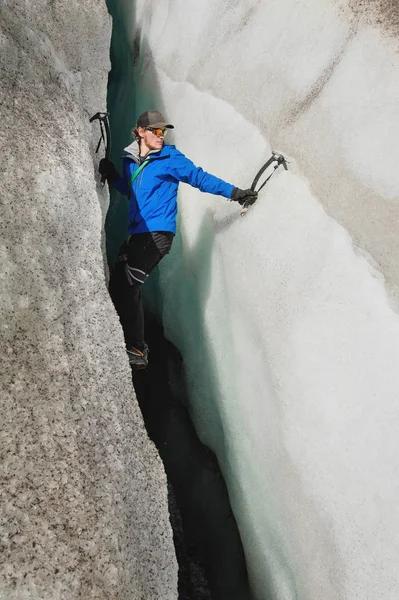 Un grimpeur libre sans assurance avec deux piolets s'élève d'une fissure dans le glacier. Escalade libre sans cordes — Photo