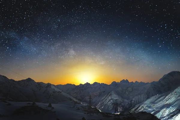 Monduntergang in den Bergen bei Nacht mit einer horizontalen Milchstraße am Himmel. Schneebedeckte Gipfel der Berge in der Nacht — Stockfoto