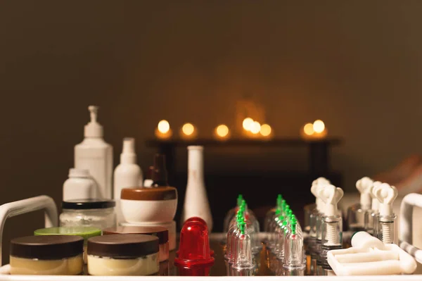 Медицинский набор стеклянных банок и поршневой вакуумный массаж в темной комнате среди горящих свечей — стоковое фото