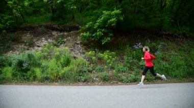 Ortalama genel planı. Tatlı kız. Kulaklığımda sarışın kız ormanın içinde kamera geçmiş çalışır. Yan görünüm