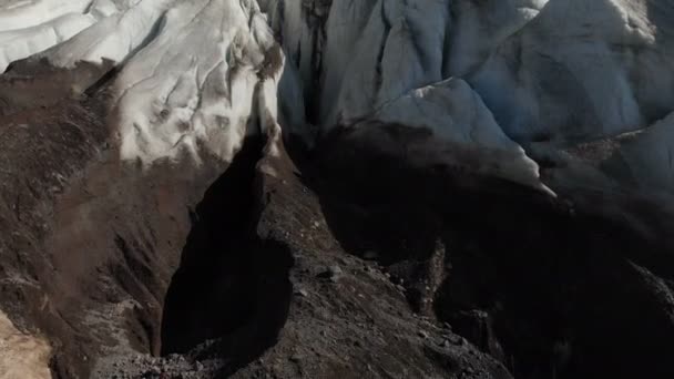 Close-up voo baixo sobre as rachaduras profundas de uma geleira rastejante montanhosa em 4K. Glaciar em pó com areia vulcânica amarela — Vídeo de Stock
