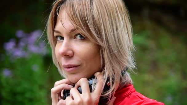 Close-up de uma linda garota loira usando fones de ouvido para correr ao ar livre na floresta — Vídeo de Stock