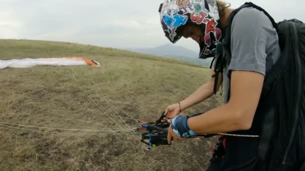 Närbild professionella paraglider pilot förbereder för start, knäppning utrustning och uträtning lyftselar — Stockvideo