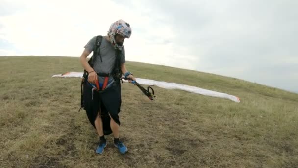 Yakın çekim profesyonel yamaçparaşütü pilot hazırlar kalkış için ekipman kadar düğmelerini ve askılar düzleştirme — Stok video